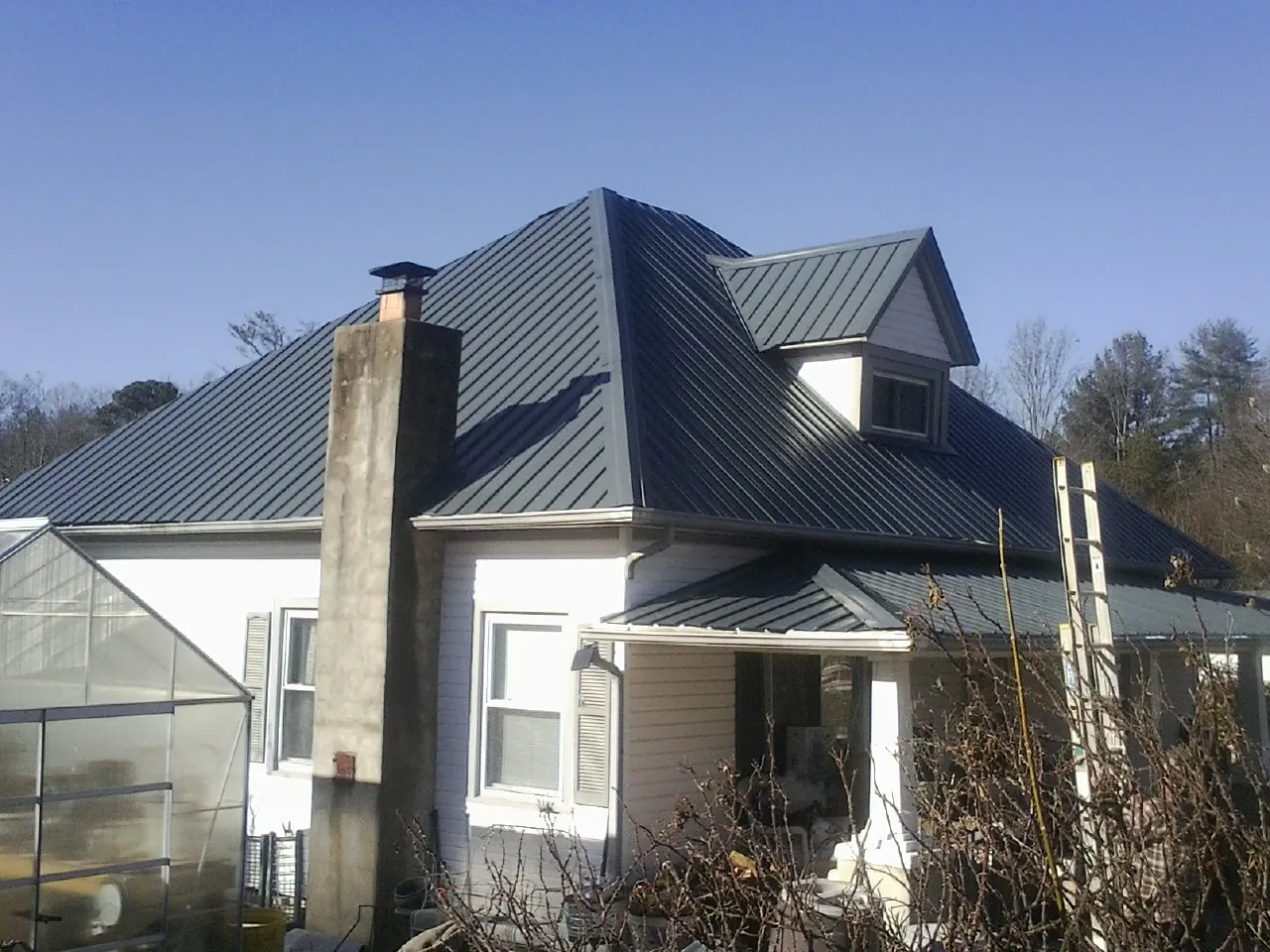 Dark blue standing seam metal roof on a white farmhouse with dormer — Slate & Tile Roof Repair by Roofing Brothers in Prosser