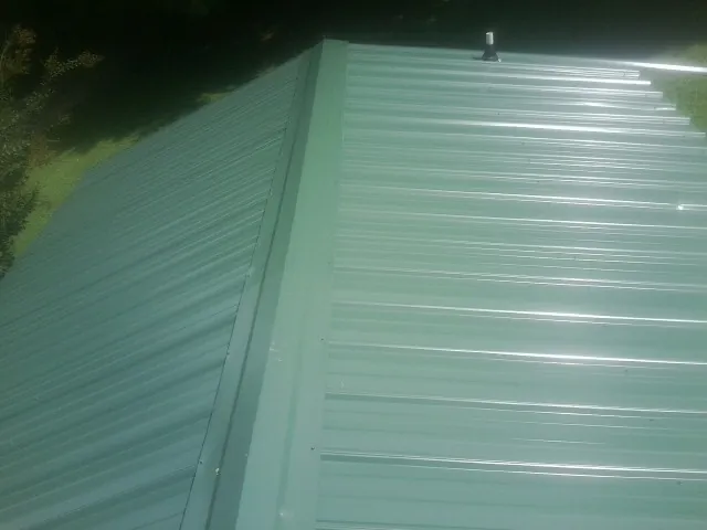 New green metal panels meeting at the ridge of a roof — Flat Roof Repair work by our crew in Prosser