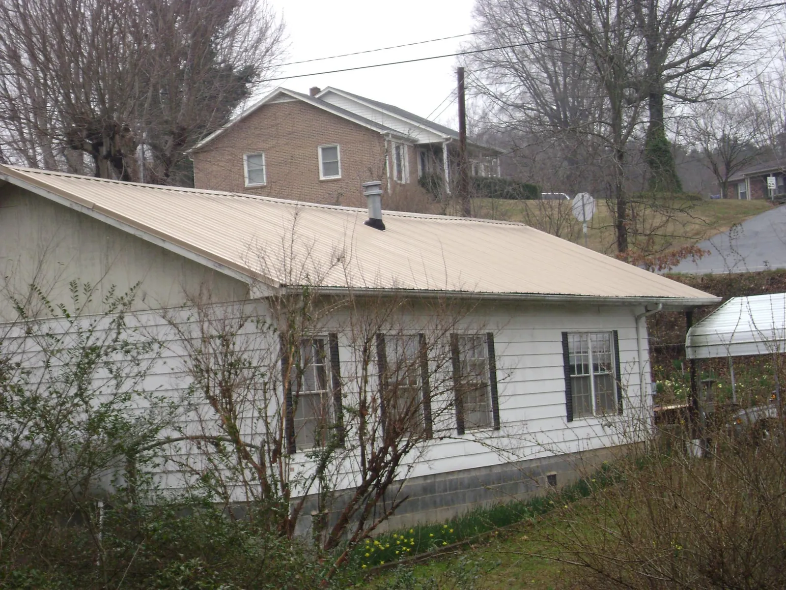 Tan metal roof on a white sided house set into a hillside — Commercial Roofing by Roofing Brothers in Prosser