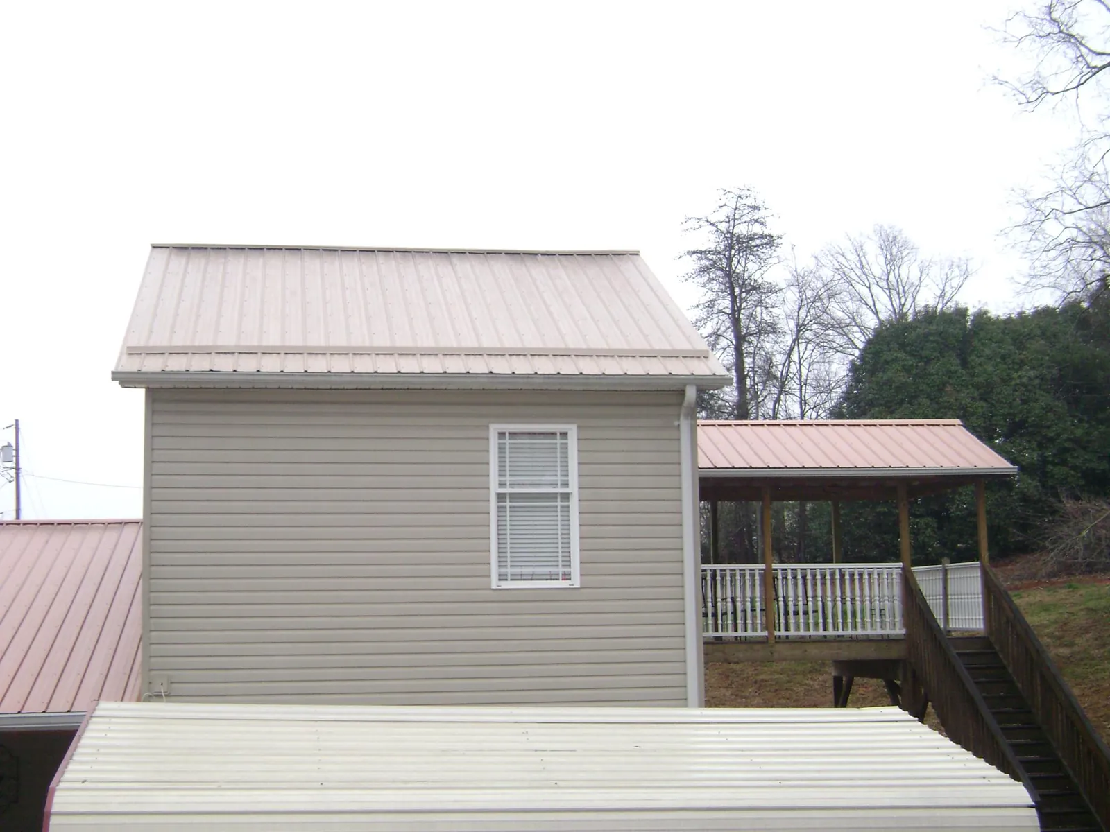 Tan metal roofs on a two story addition and attached porch, from a Roof Replacement job in Prosser