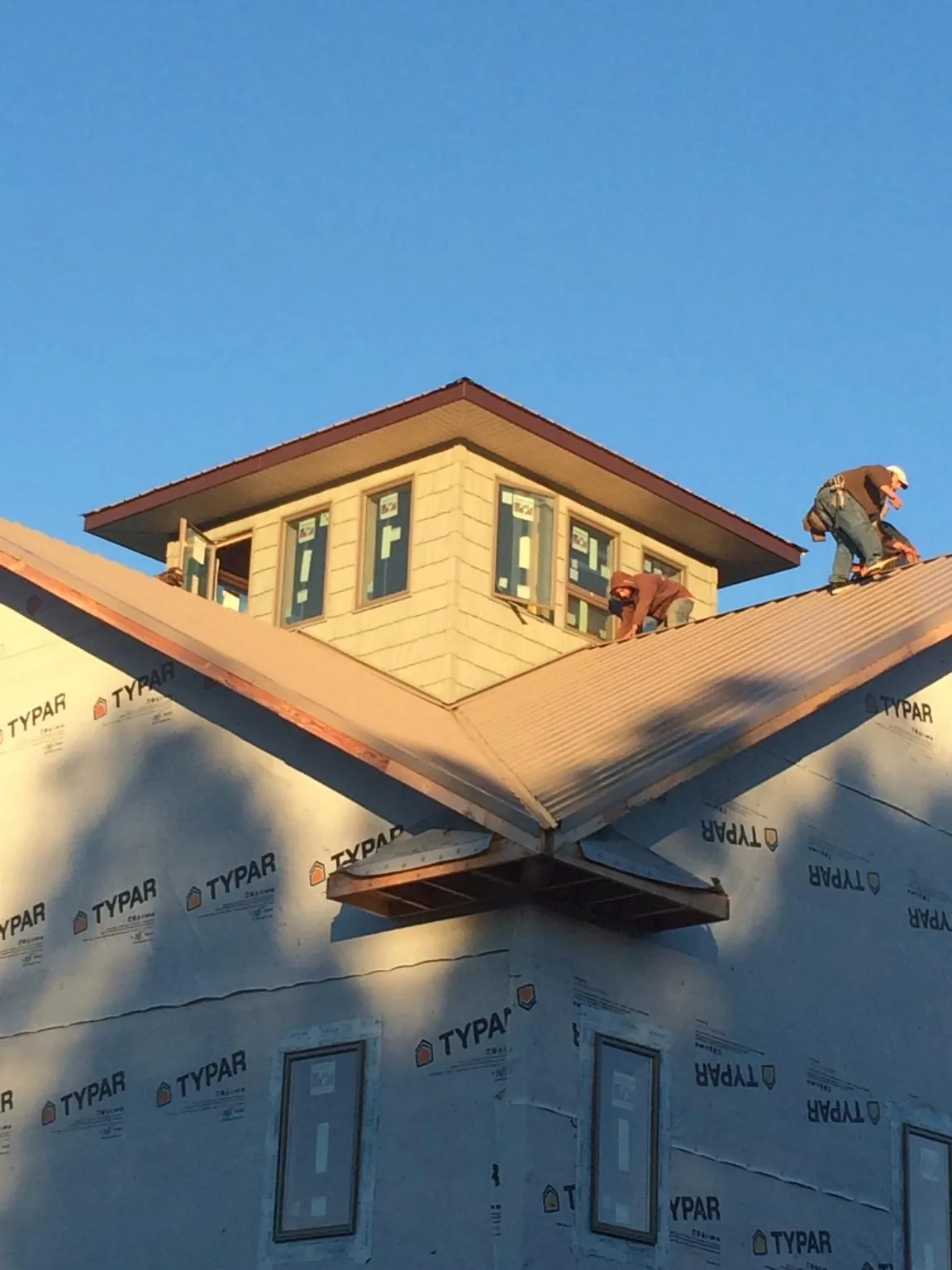 Roofers working around a rooftop cupola on a new metal roof at sunset — Roof Waterproofing in Prosser by Roofing Brothers